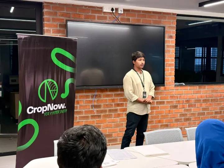 A team member presenting beside a CropNow banner