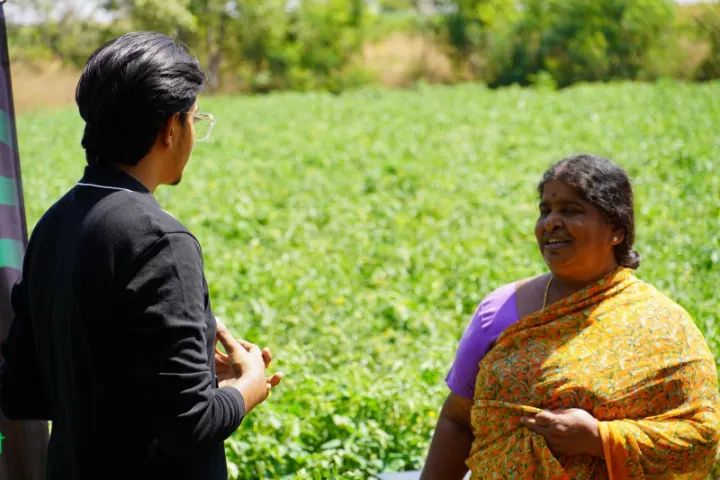 A CropNow team member listening to a woman farmer in her field